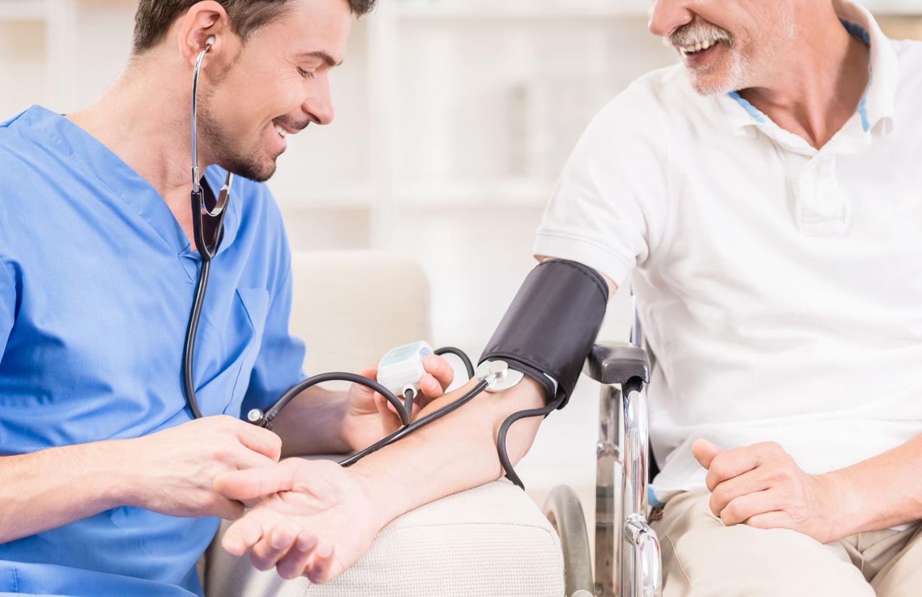 Ein Arzt überprüft den Blutdruck eines Mannes, der entspannt auf einer Couch sitzt.