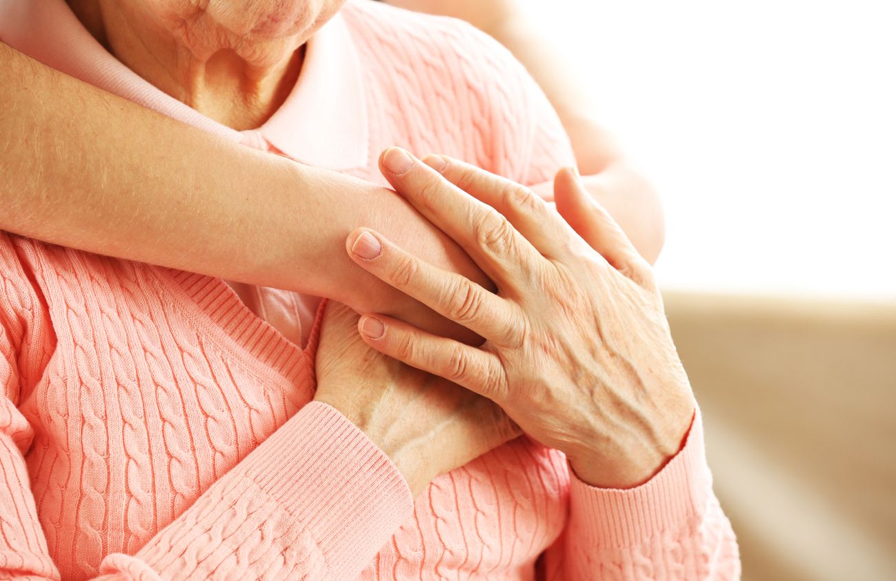 Eine ältere Frau wird von einer anderen Person umarmt.