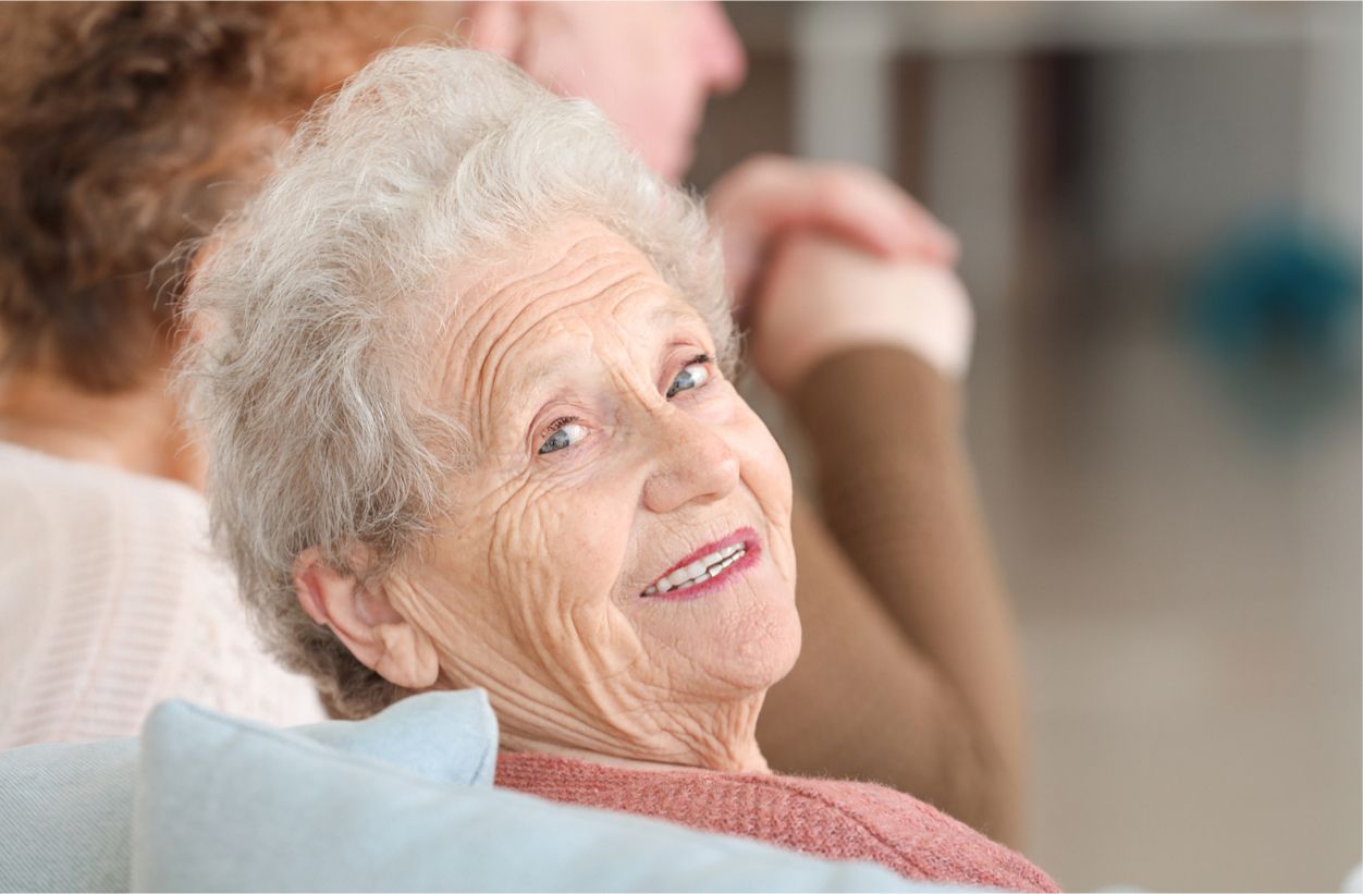 Ältere Frau schaut lächelnd über Ihre Schulter